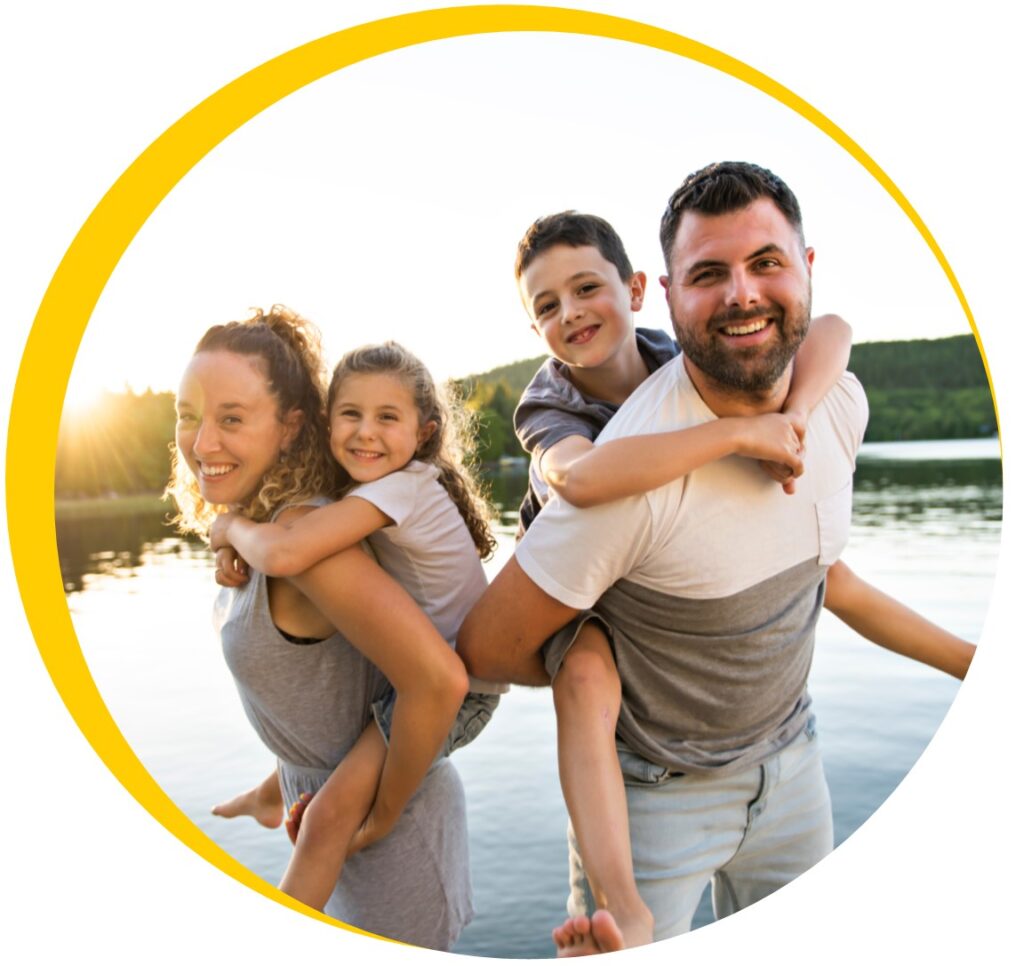 Family with kids riding piggy back at the lake